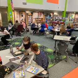 Students and teachers interacting in the Academy International Elementary School library.